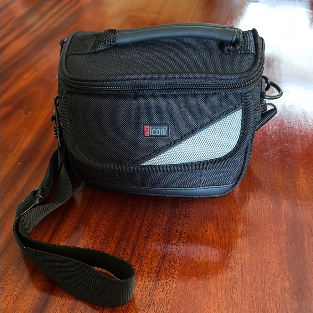 📷 Small iCon black camera bag with handle and shoulder strap.